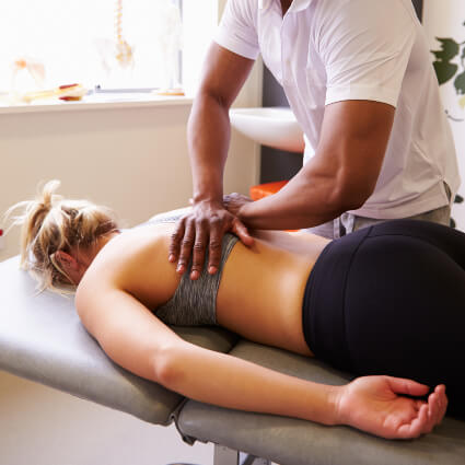 Male chiropractor adjusting female patient's back