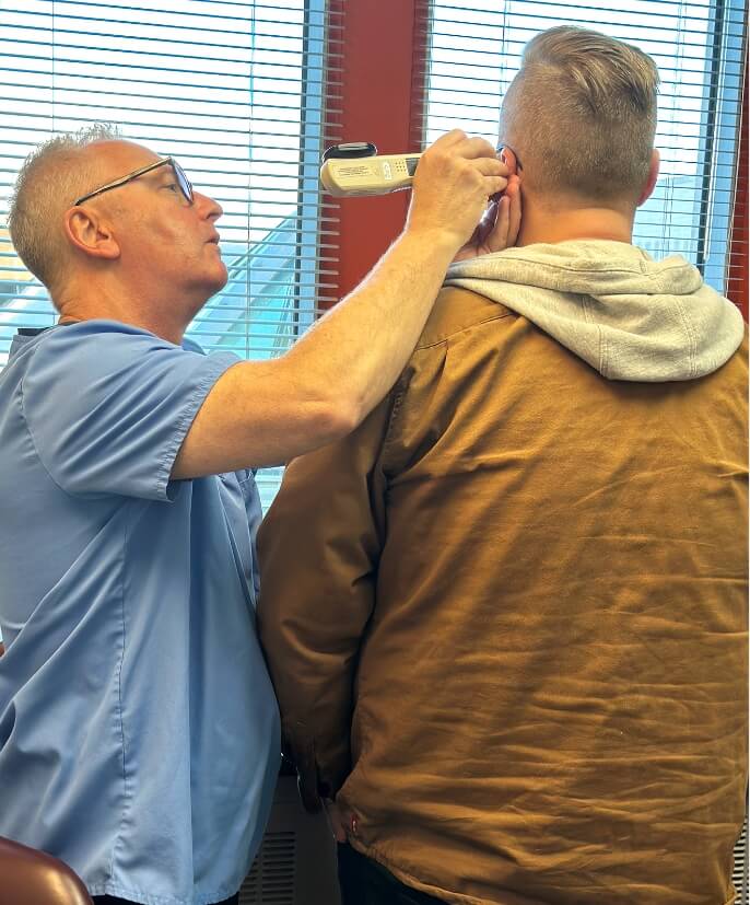 Chiropractor checking patients ear