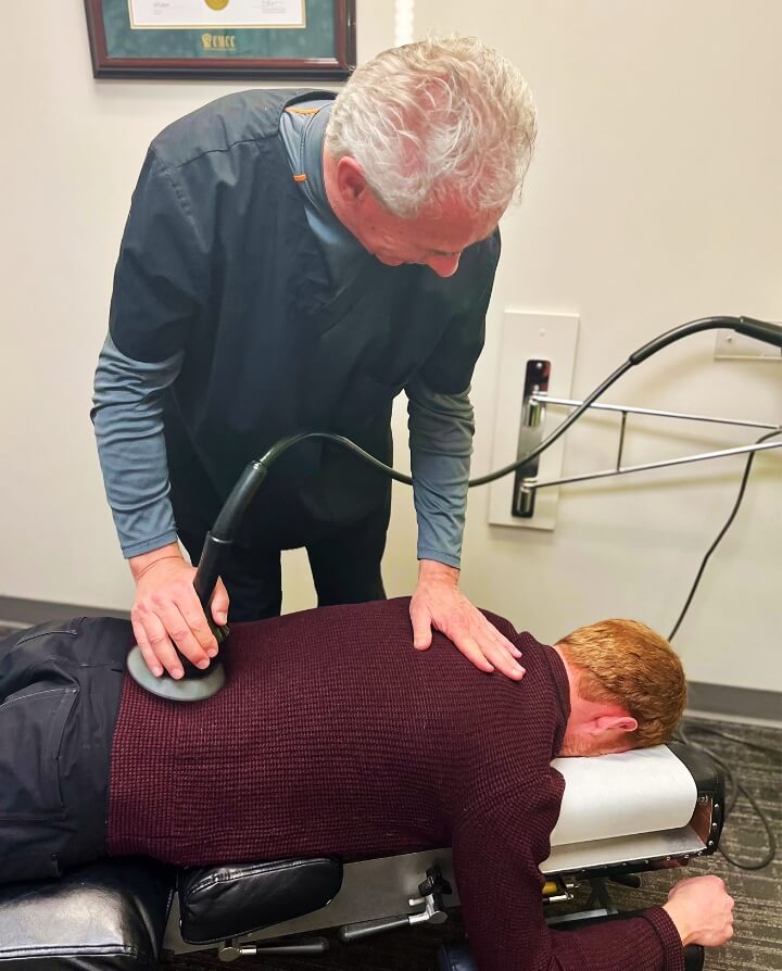 Chiropractor using tool on patients back