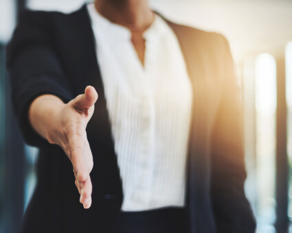 Business professional reaching out to shake hand