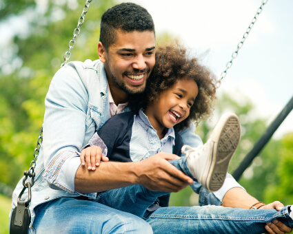 Dad and young daughter playing on swing