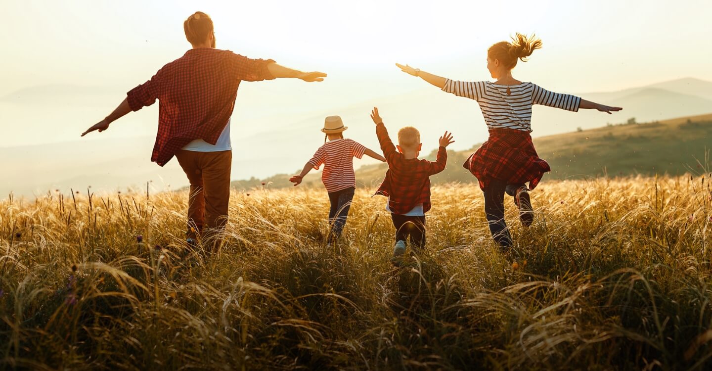 family of 4 running outdoors at sunset