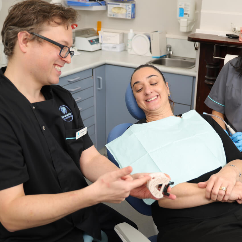 Brunswick dentist Dr Chris showing patient a tooth model