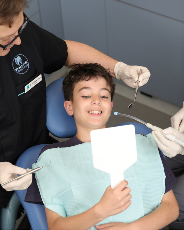 child looking at his teeth on the mirror