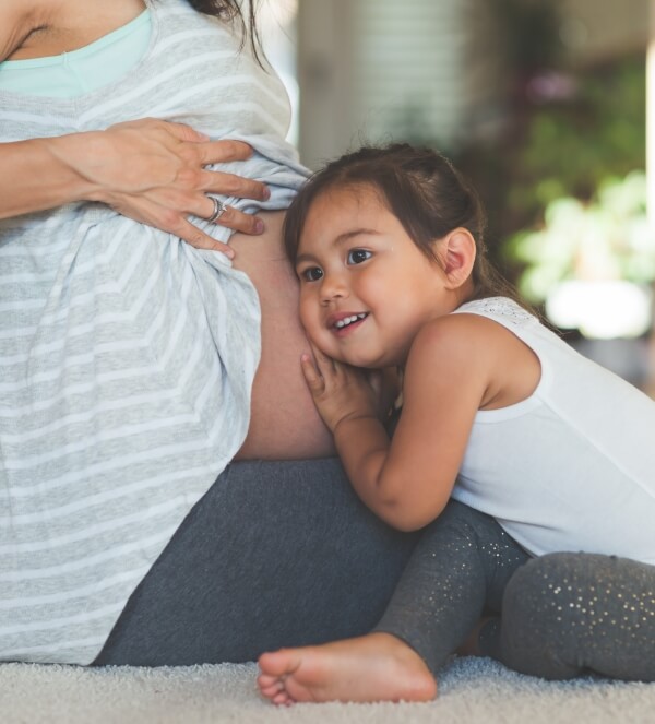 smiling kid listening to pregnany moms belly