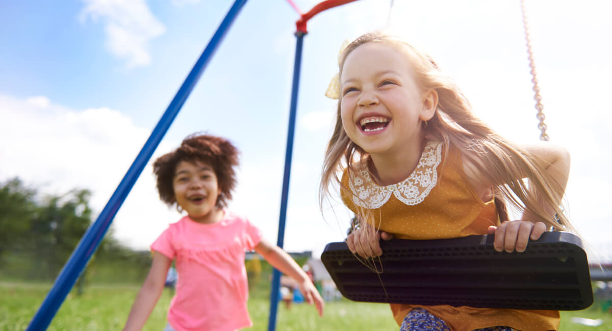 Two kids playing on a swing