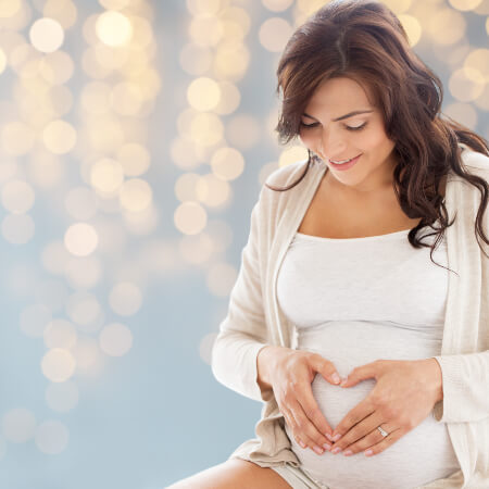 Pregnant woman making heart shape with hands on belly