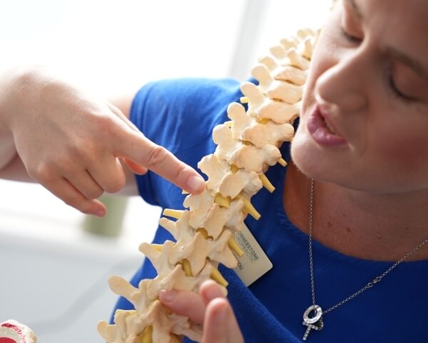 About Us Chiropractor pointing at spine model