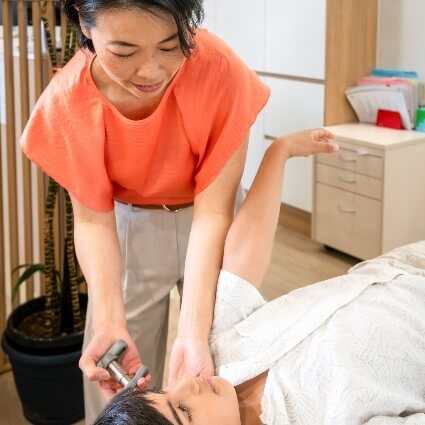 Dr Irene using activator tool on patient