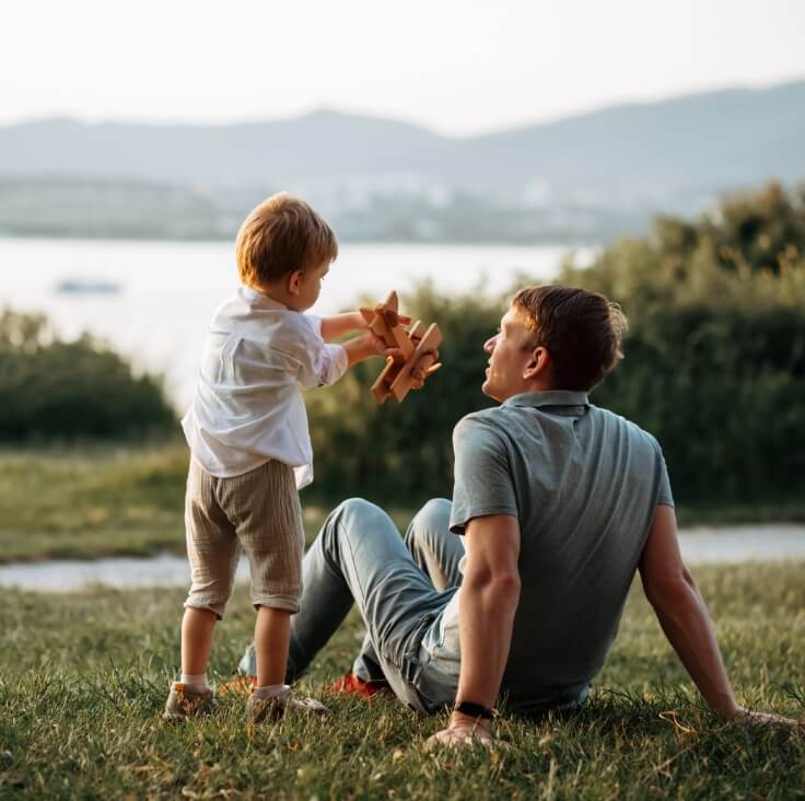 father and son sitting by water