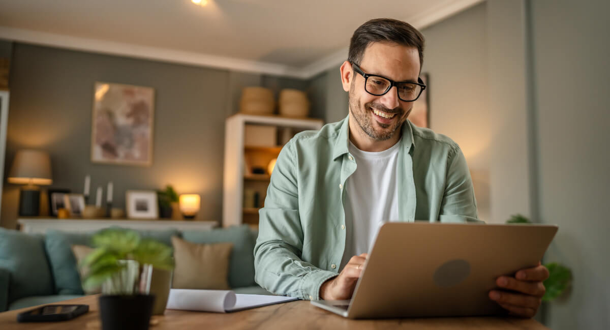 Smiling man wearing glasses busy on a laptop