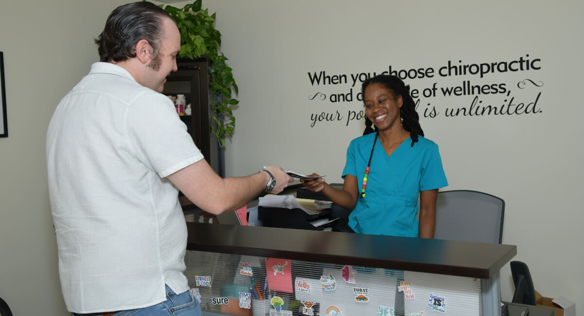 Female staff member at Dixon Chiropractic handing over paperwork to a patient