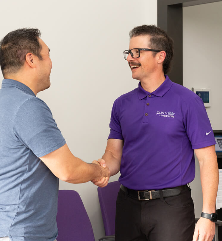 Vienna patient being greeted with a handshake at Pure Chiropractic