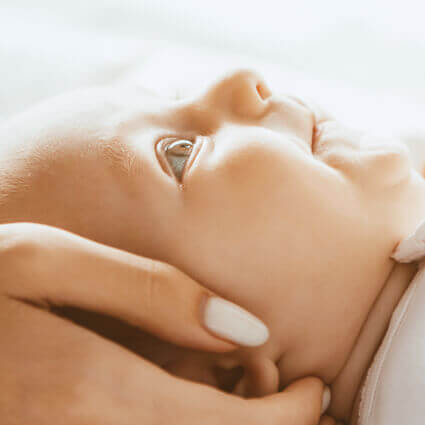 baby-lies-on-back-embraced-by-parents-hands-sq