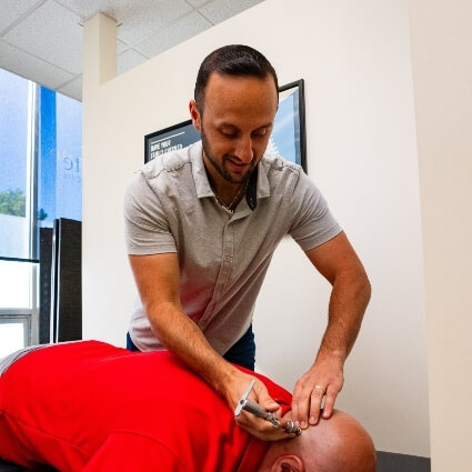 Wappingers Falls chiropractor adjusting patients neck with tool