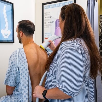 Dr Kristina using softwave tool on patients back