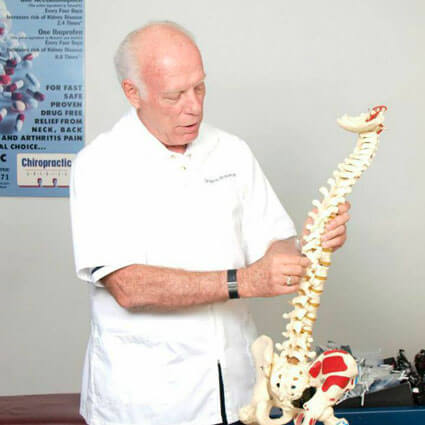 Dr. Harrie Wolverton holding a model of a spine.
