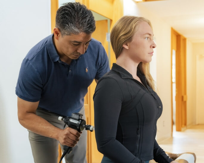 Colorado Springs chiropractor using a tool to adjust a female patient