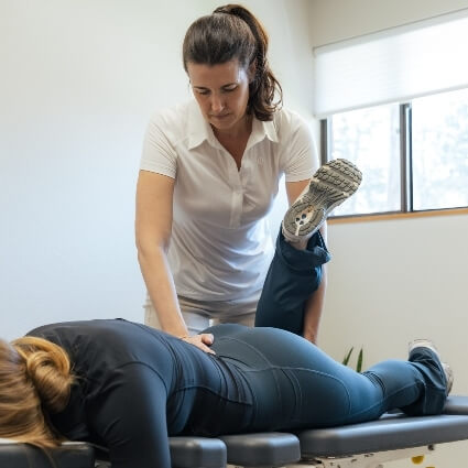 Female Naprapathic Medicine practitioner adjusting patient's leg