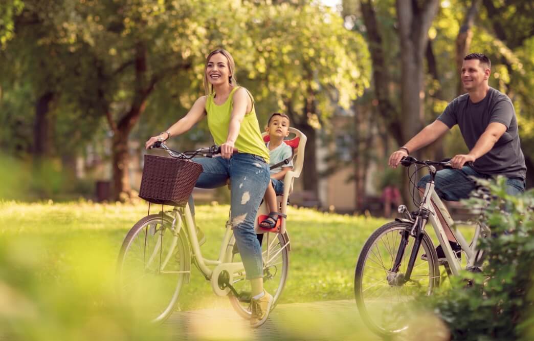 mom, dad, and child riding bikes in the park