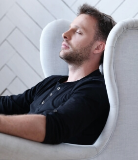 man sitting in chair with eyes coesd