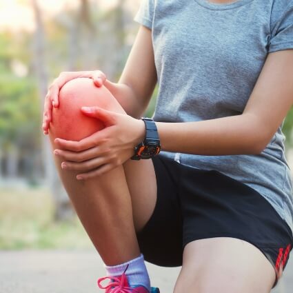 woman kneeling holding her knee in pain