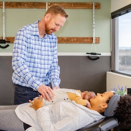 Dr John adjusting baby who is laying on mom