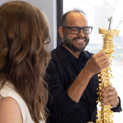 Chiropractor discussing spine model with patient