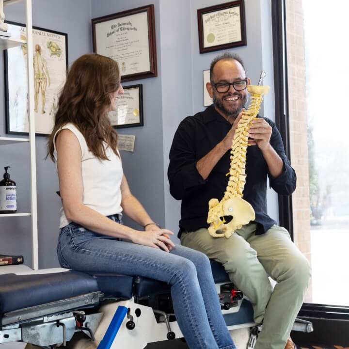 Austin chiropractor discussing spine model with female patient
