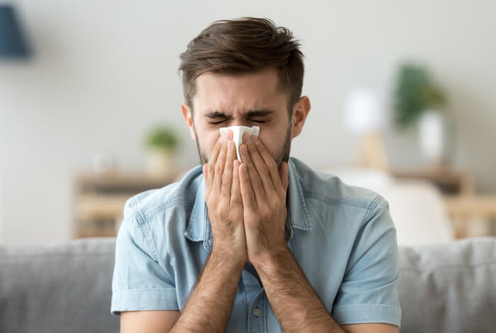 man blowing his nose into a tissue