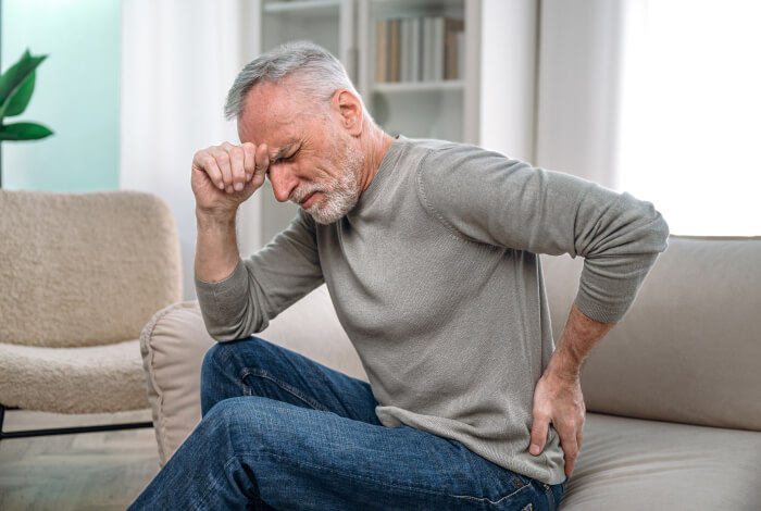 man sitting on a couch with low back pain