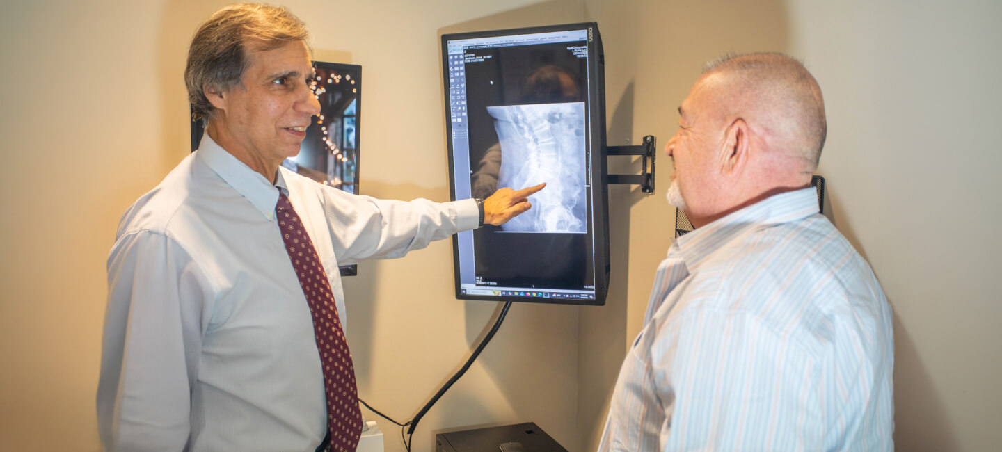 Oak Creek chiropracor Dr Gavric pointing at patients xrays