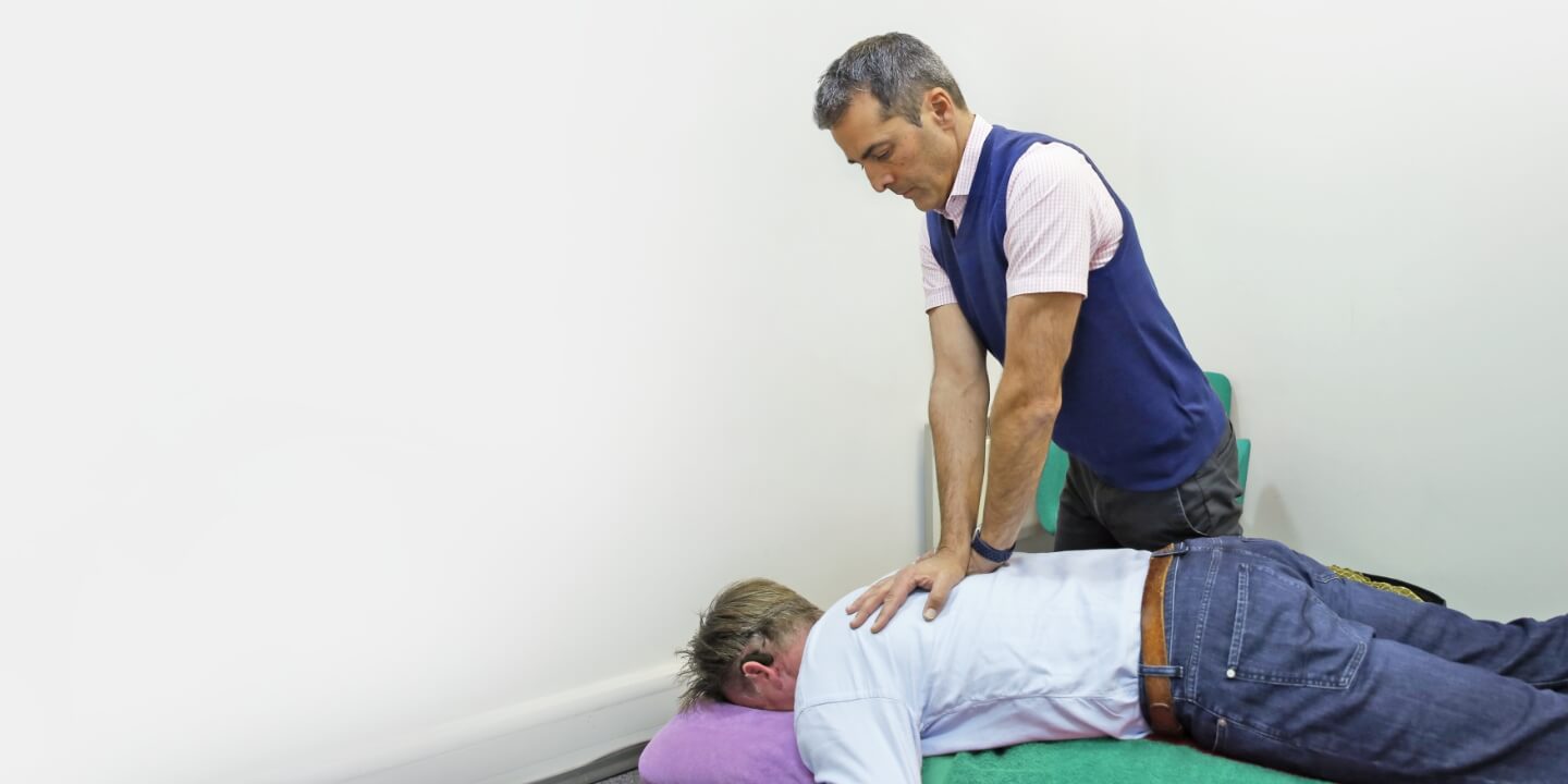 East Horsley chiropractor adjusting patient's upper-back