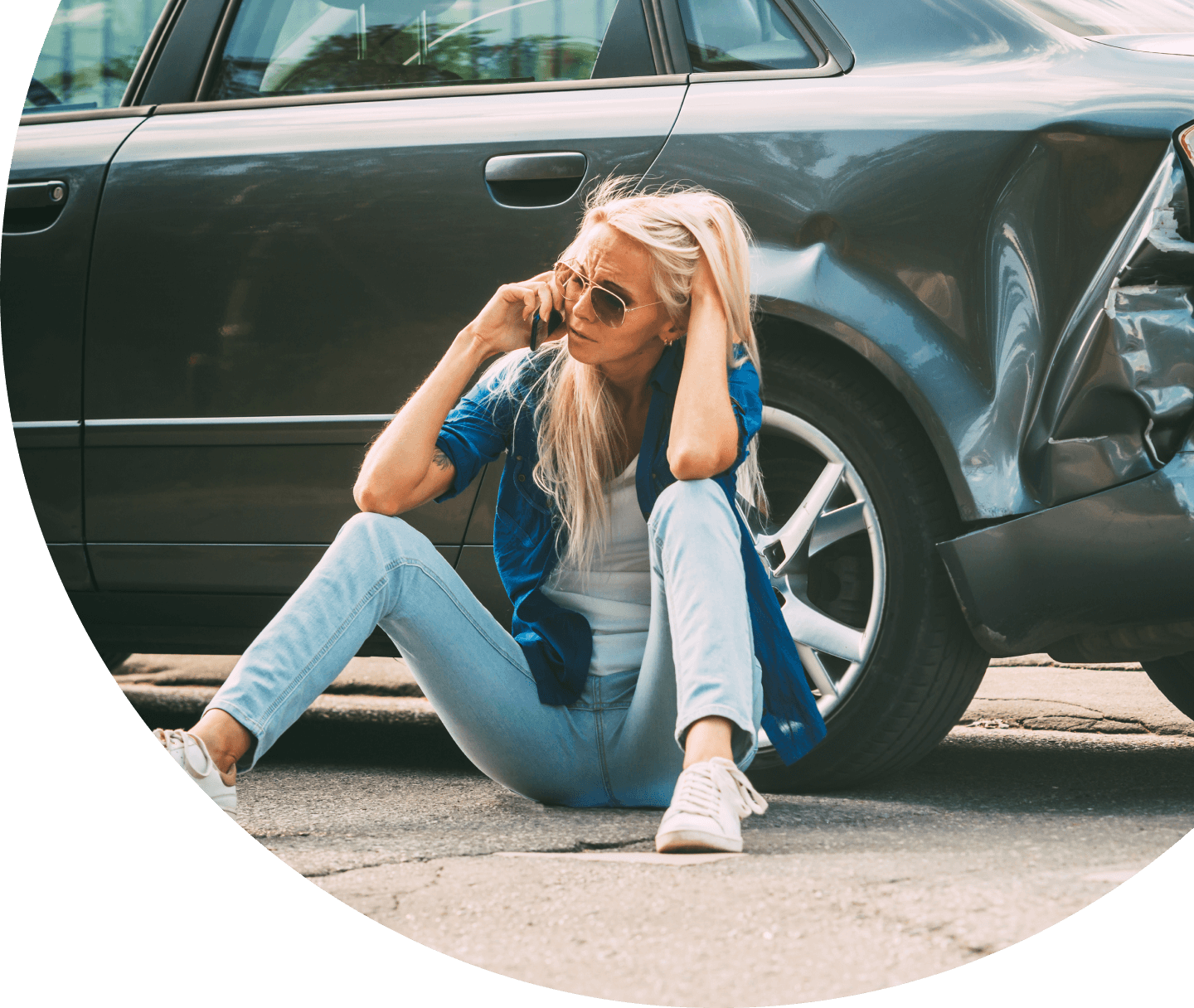 woman sitting near car looking worried after auto accident
