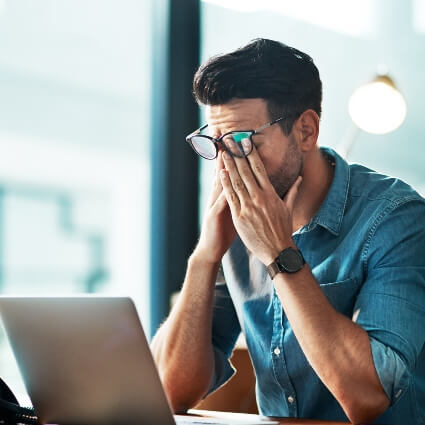 man sitting at laptop with sinus pain