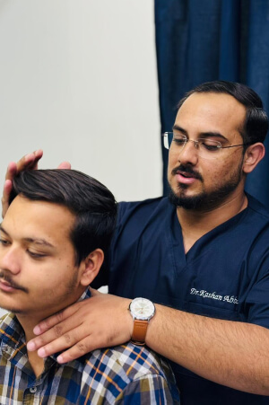Dr. Kashan Abbas adjusting a male patient
