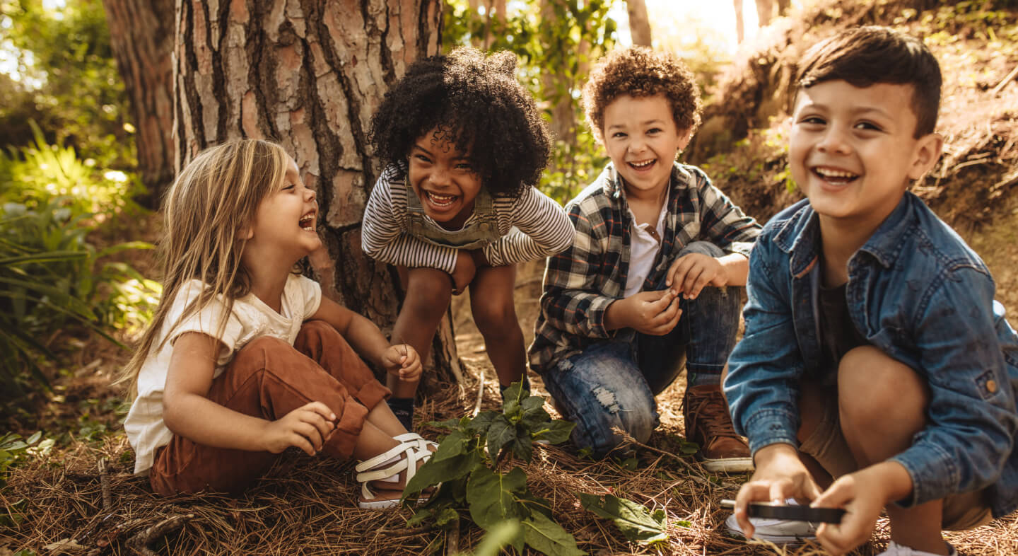 four children laughing while playing outdoors