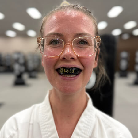 Close up photo of a woman wearing a judo outfit and a mouthguard
