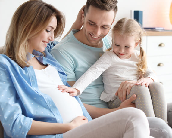 pregnant mom and dad with baby smiling