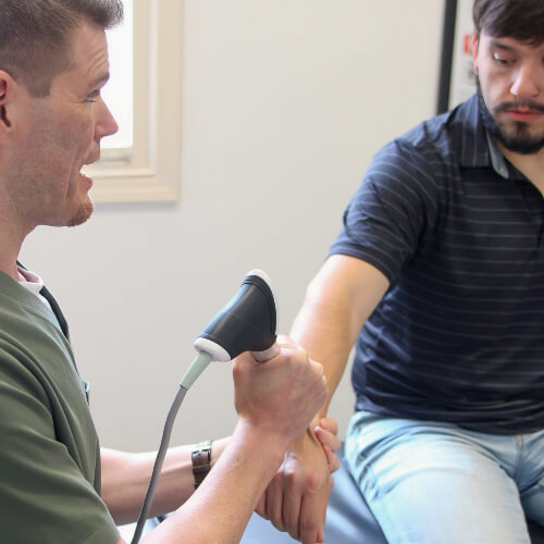 Chiropractor using Laser Therapy to treat a patient