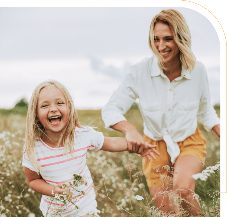 mom and daughter smiling while walking through flowers