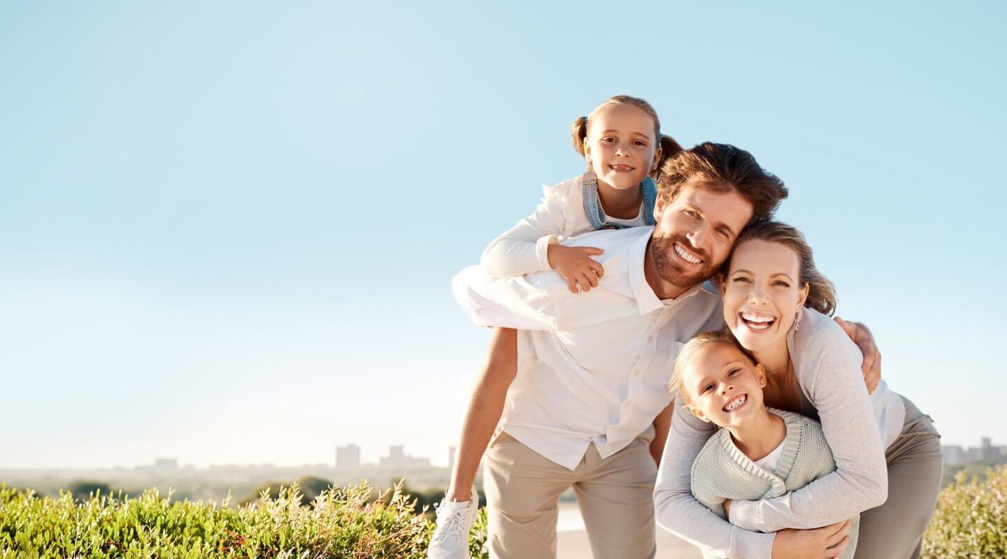 family of 4 smiling together on the beach