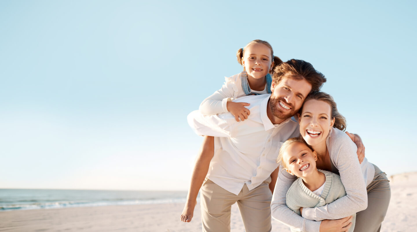 family of 4 smiling together on the beach