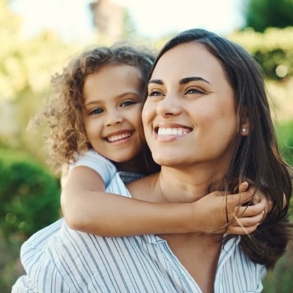 smiling mom with daughter riding on her back