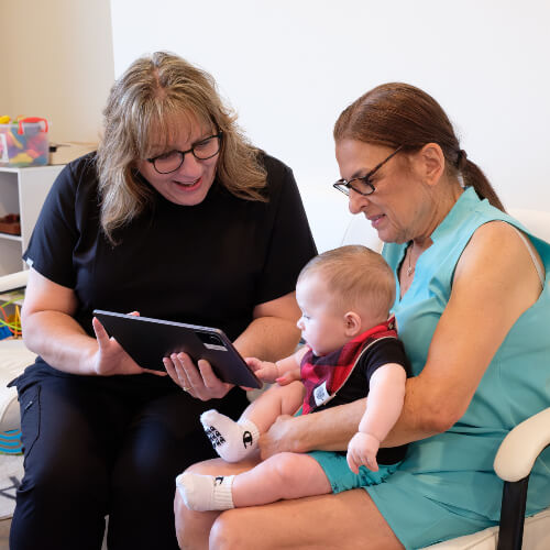 Chiropractor talking to patient holding a baby