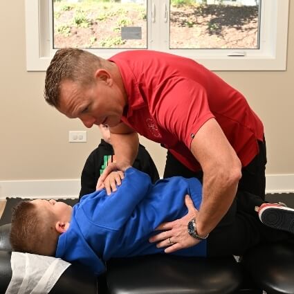 Boy with blue sweater receiving a chiropractic adjustment