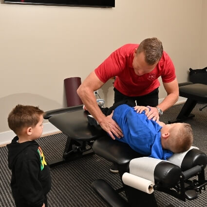 Little boy watching his brother receiving a chiropractic adjustment
