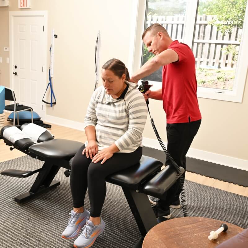 Dr. Buss of Harmony Chiropractic using a chiropractic tool to adjust patient