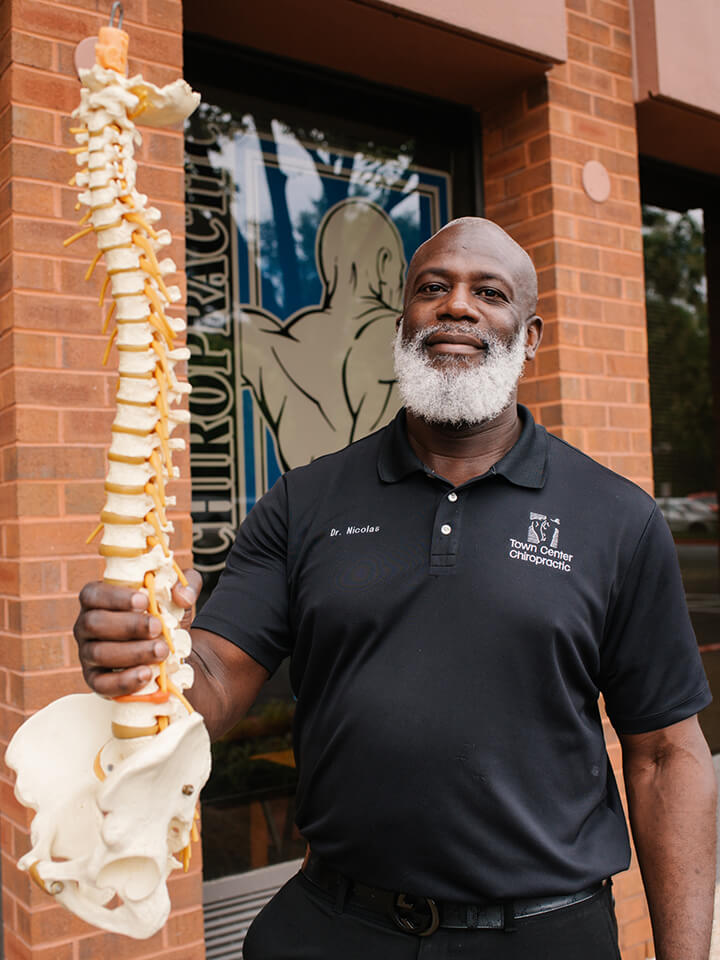 Dr. Phillip Nicolas holding model of a spine