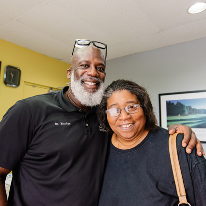 Dr. Phillip Nicolas with his arm around a happy patient